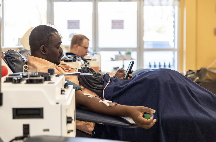 Plasma donor seated in a donation chair using a smartphone